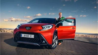 Roter Toyota AYGO X mit geöffneter Tür vor Bergkulisse