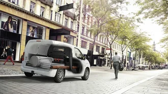 Weißer Toyota Proace City von hinten fährt in einer Stadt. Der Innenraum ist sichtbar