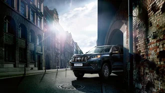 Toyota Land Cruiser fährt aus einem alten Torbogen in die Straße einer Altstadt