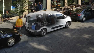 Weißer Toyota Proace City von der Seite steht in einer Stadt auf einem Parkplatz. Der Innenraum ist sichtbar