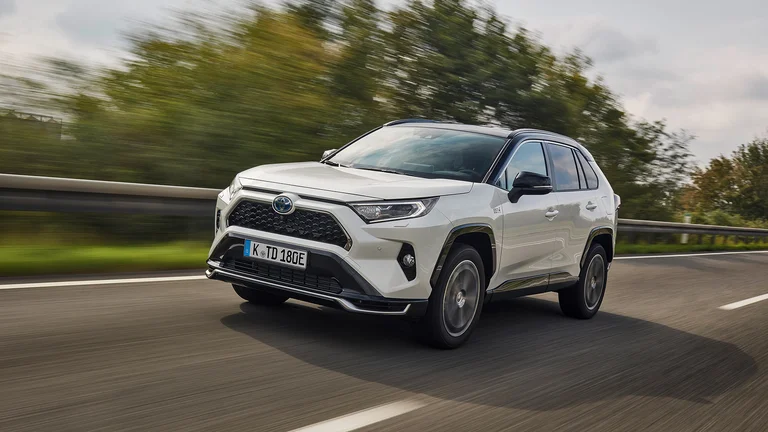 Weißer, fahrender Toyota Rav4 bei schönem Wetter auf einer Landstraße